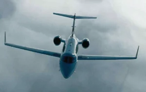 Learjet 45 private jet in flight against a cloudy backdrop.