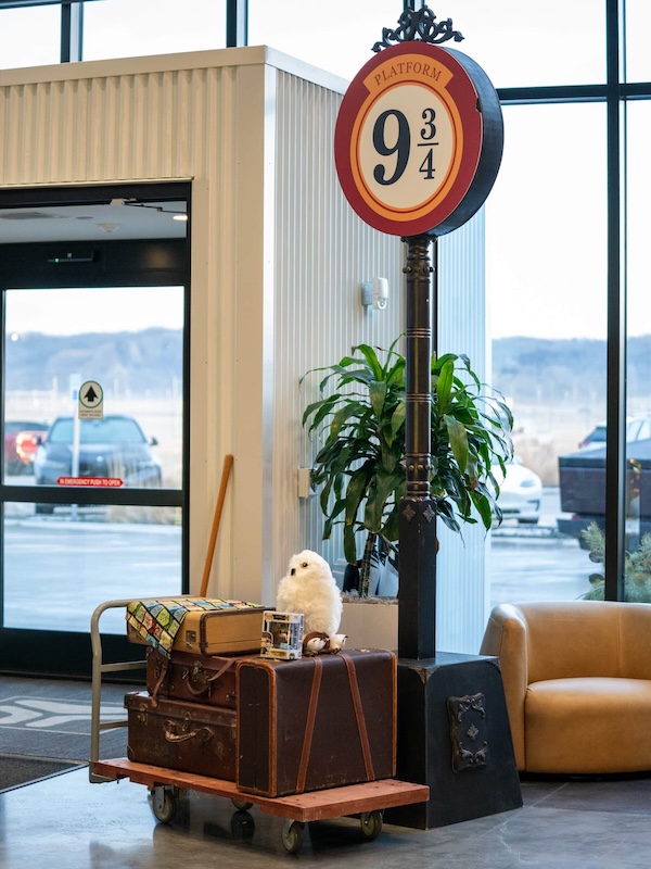 The space had been thoughtfully transformed with Harry Potter–inspired details, including a balloon arch, floating candles, and a Platform 93/4 display complete with themed luggage and Hedwig the owl.